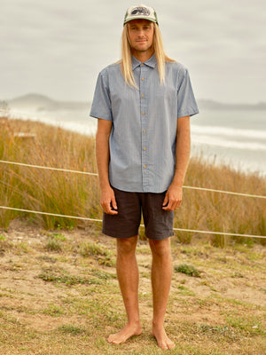 Man wears a button up shirt with blue gray stripes